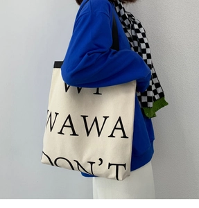 Side view of large off-white canvas tote bag with bold black letters for students