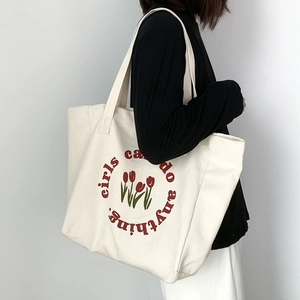 Close-up of canvas tote bag featuring red tulips and girls can do anything print