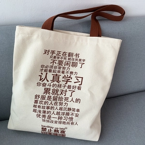 Detail of off-white canvas tote bag featuring motivational text and wide brown handles