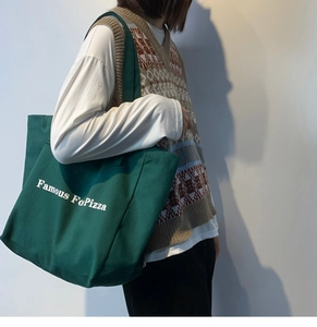 Détail du grand sac cabas en toile verte avec lettrage Famous For Pizza blanc brodé