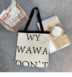 Macro view of canvas tote bag with letter print and durable strap in a student desk setting