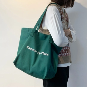 Gros plan sur un grand sac cabas en toile vert foncé avec lettrage Famous For Pizza blanc