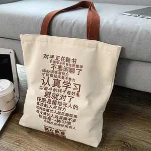 Detailed shot of canvas tote bag with motivational text next to a laptop