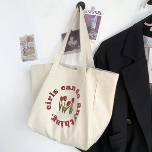 Close-up of girls can do anything slogan and tulip print on canvas tote bag
