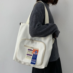 Detail der weißen Canvas-Tasche mit Bordkarten-Etikett und Reißverschlusstasche
