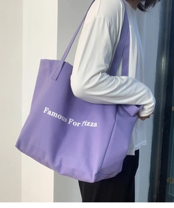 Détail d'un grand sac cabas en toile violette avec texte Famous For Pizza à l'épaule