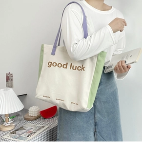 Detail view of large canvas tote bag featuring macaron color blocking and Good Luck print