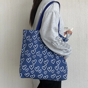 Detailed close-up of dark blue canvas tote bag featuring white heart print on a shoulder