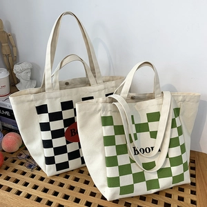 Close-up of canvas tote bag showing magnetic buckle closure and letter print detail