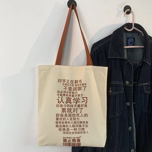 Detail of beige canvas tote bag with brown woven handles and Chinese motivational text