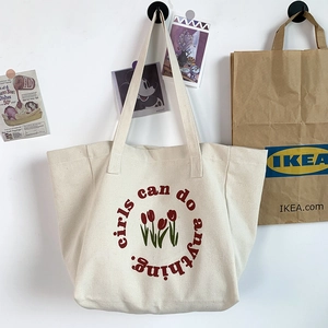 Detail of canvas tote bag showing red tulip embroidery and girls can do anything slogan