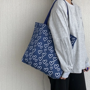 Close-up of navy blue canvas tote bag with white hand-drawn heart patterns and strap