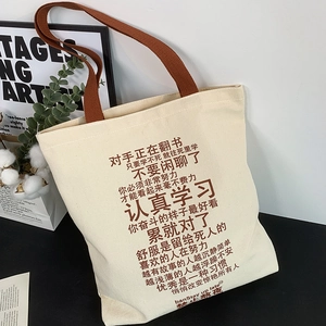 Detail of off-white canvas tote bag featuring motivational text and brown ribbon handles