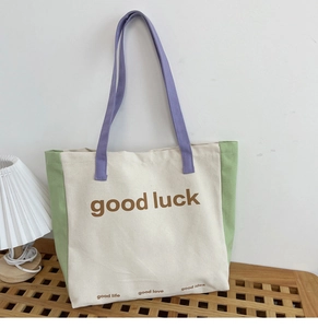 Close-up of color-block canvas tote with Good Luck print on a wooden bench