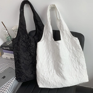 Détail de la texture jacquard florale brodée sur des sacs fourre-tout blancs et noirs