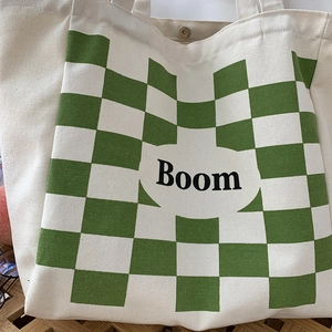 Detail of canvas tote bag with green checkerboard pattern and Boom letter print