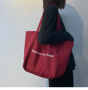 Détail du sac fourre-tout en toile bordeaux robuste avec imprimé Famous For Pizza sur modèle