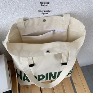 Détails de la fermeture par bouton pression et de la poche zippée du sac en toile