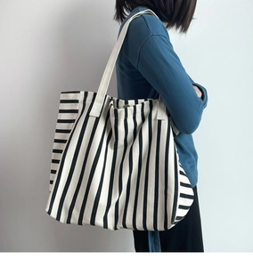Close-up of the textured black and white striped canvas tote bag worn by a model