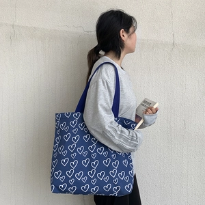 Detail of navy blue canvas tote bag with white heart print and large capacity