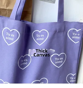 Détail du sac en toile violette avec motifs de cœurs blancs et texte brodé en français