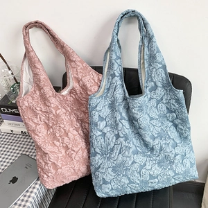 Détail de sacs cabas en jacquard floral rose et bleu sur une chaise de bureau