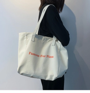 Détail du grand sac cabas en toile blanche avec imprimé Famous For Pizza sur bandoulière