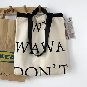 Close-up of large canvas tote bag featuring black lettering and wide fabric handles