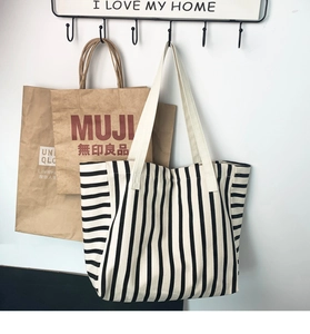 Detailed view of striped canvas tote bag with wide white shoulder straps and large capacity