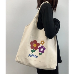 Detail view of off-white canvas tote bag featuring floral print and HAPPY BIRTHDAY text