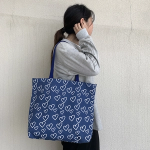 Detail of large navy canvas tote bag with white heart patterns and fabric handle