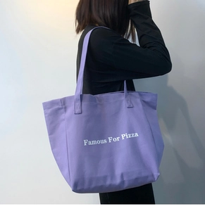 Vue latérale d'un grand sac cabas violet en toile avec imprimé Famous For Pizza