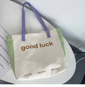 Detail view of canvas tote bag with good luck print and colorful pastel stitching