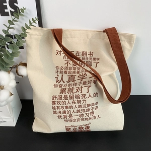 Detail of cream canvas tote bag featuring motivational text and sturdy brown handles