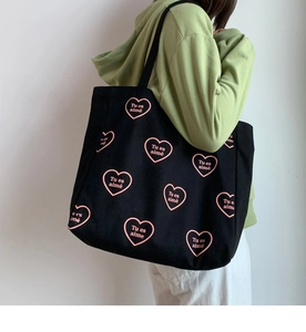 Détail du sac cabas en toile noire avec motif cœurs roses et texte Tu es aimé