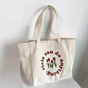 Detail of canvas tote bag with red tulip print and Girls can do anything text