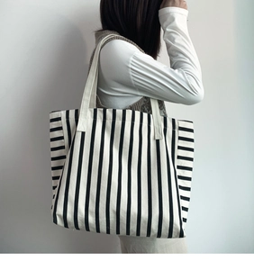 Detail of a large striped canvas tote bag shown on a shoulder for daily use