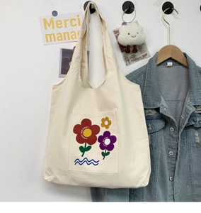 Detail of canvas tote bag featuring floral print pocket with Happy Birthday text