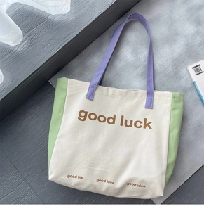 Detail of color-block canvas tote bag with good luck print and green side panels