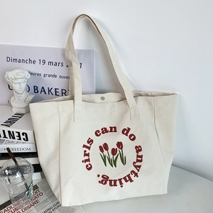 Detailed view of canvas tote bag featuring red tulips and girls can do anything text