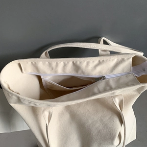 Minimalist canvas tote bag featuring secure top zipper and internal zip pocket detail