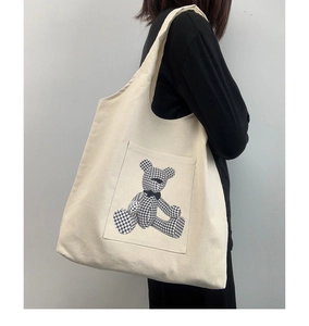 Detail of canvas tote bag featuring a cute houndstooth bear pocket and spacious design