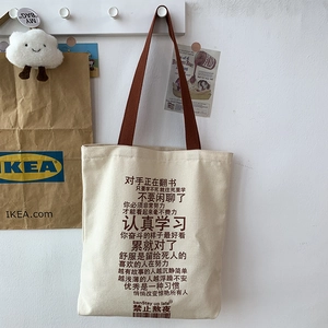 Detail of canvas tote bag with brown straps featuring humorous Chinese typography print