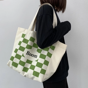 Detail of large canvas tote bag showing green checkerboard print and bold Boom text