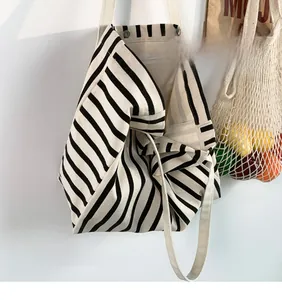 Detail shot of striped canvas tote bag showing metal buckle and inner zipper pocket