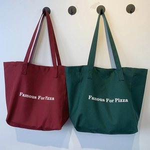 Détail de sacs fourre-tout en toile bordeaux et vert foncé avec texte Famous For Pizza