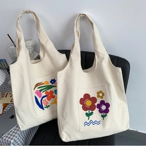 Detail of cream canvas tote bags featuring colorful floral prints and wide handles