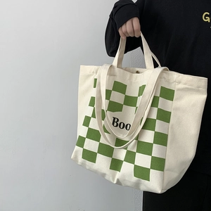 Detail of canvas tote bag with green checkerboard pattern and dual handle straps