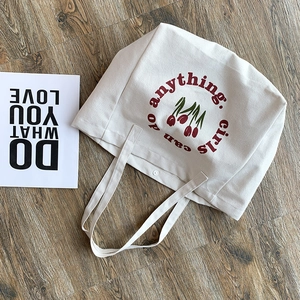 Detail of canvas tote bag featuring tulip floral print and girls can do anything slogan