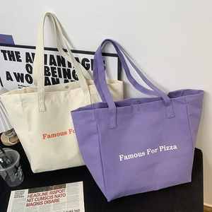 Détail de sacs cabas en toile minimalistes beige et violet avec imprimé Famous For Pizza